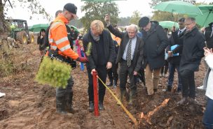 Un groupe de personnes regarde le ministre de l'agriculture et de la forêt Marc Fesneau planter un pin.