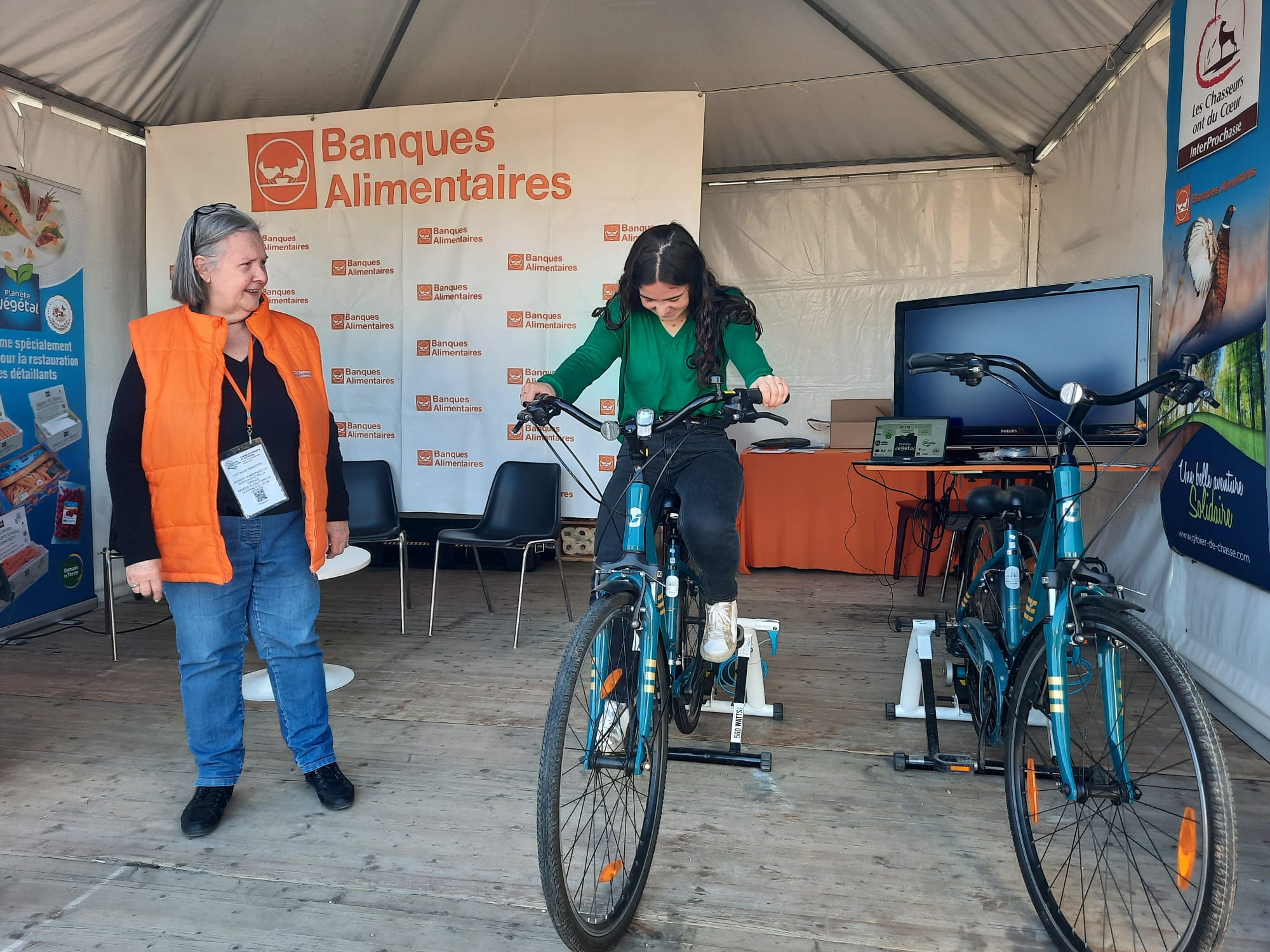 Pierrette Castagne, responsable communication Banque Alimentaire Bordeaux-Gironde, anime une session vélo avec une jeune fille.