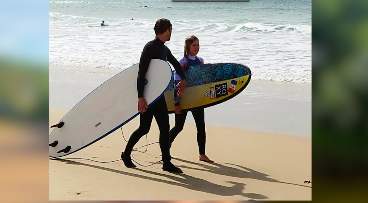Lou planche de surf sous le bras avec son binôme 