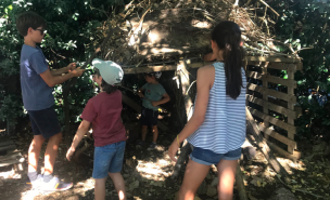 Trois enfants dans la nature construisent une cabane