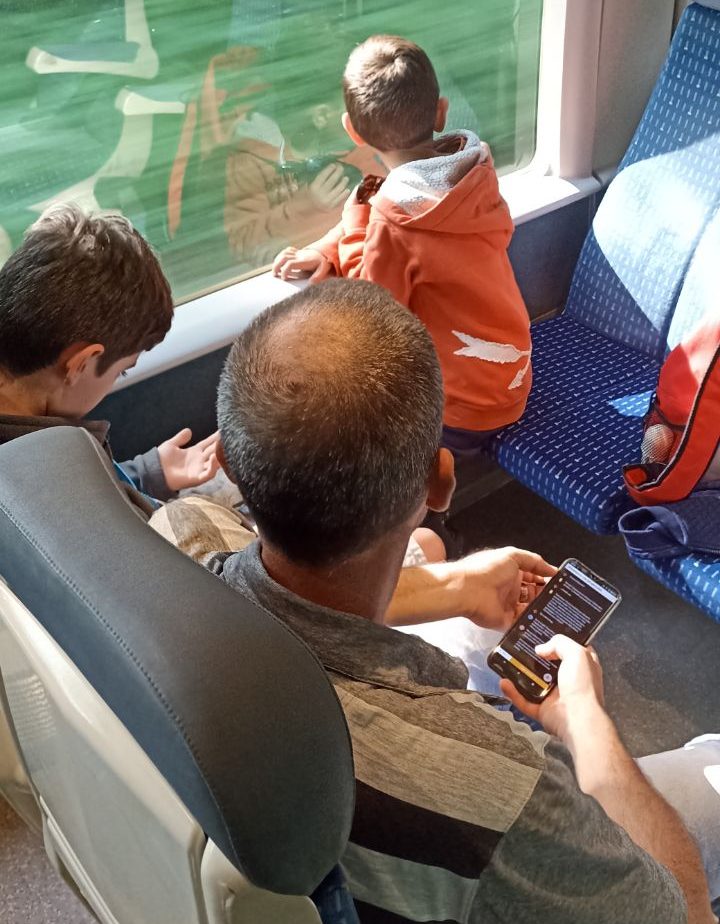 Deux enfants et leur papa, téléphone ne main, dans un train