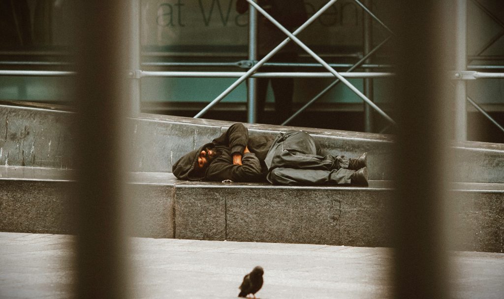 Une personne à la rue allongée sur le sol.