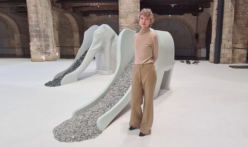 Nina Beier à côté de son œuvre Traffic, deux toboggans-éléphants, l'un remplis de cailloux, l'autre d'ardoise.
