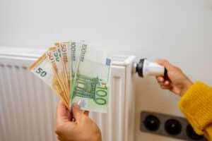 person holding euro banknotes near heater at home