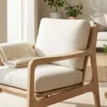 Fauteuil moderne Zara Home en bois clair avec coussins beiges et plaid, dans un salon lumineux et accueillant.