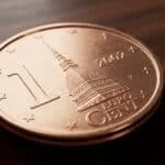 Une pièce de 1 centime d'euro italien de 2002 posée sur un support en velours rouge.