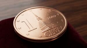 Une pièce de 1 centime d'euro italien de 2002 posée sur un support en velours rouge.