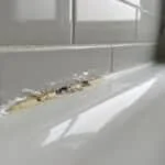Joint silicone moisi superposé sur un ancien joint dans une baignoire.