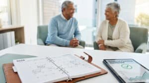 Un couple de retraités souriant discutant à côté d'un agenda 2026 ouvert et d'une tablette.